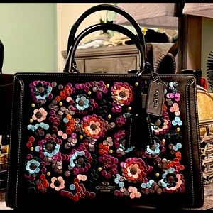 A brand new black leather coach with flower appliqué